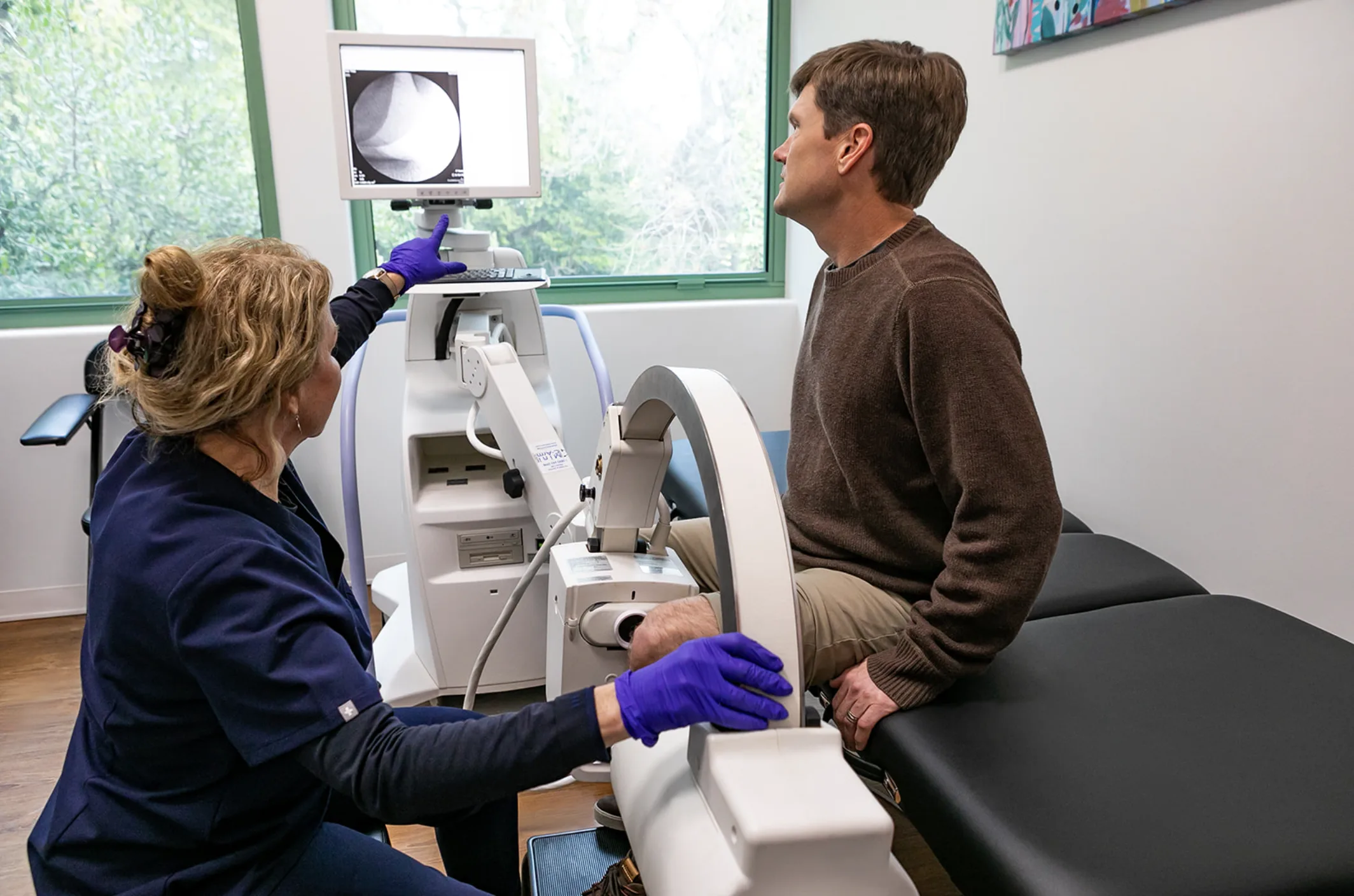 Clinician treating a patient knee with a therapy device at Marin Joint Health